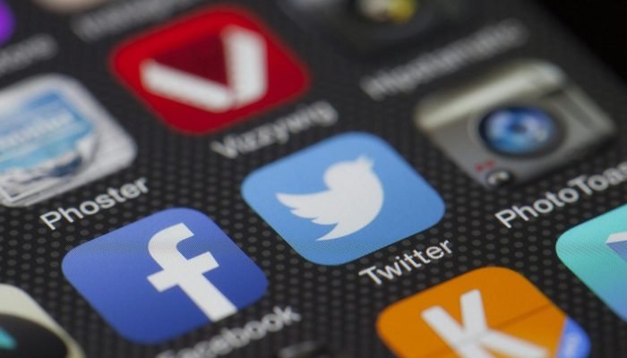 A detailed close-up of social media icons on a smartphone screen, including Facebook and Twitter.
